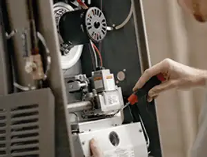 Furnace repair technician inspecting internal components and wiring in Pittsburgh, PA