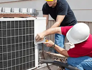 HVAC technicians repairing an outdoor AC unit on a rooftop in Pittsburgh, PA
