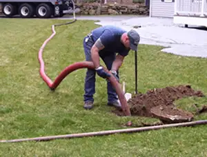 Septic pumping technician servicing a residential septic tank with a vacuum hose in Pittsburgh, PA