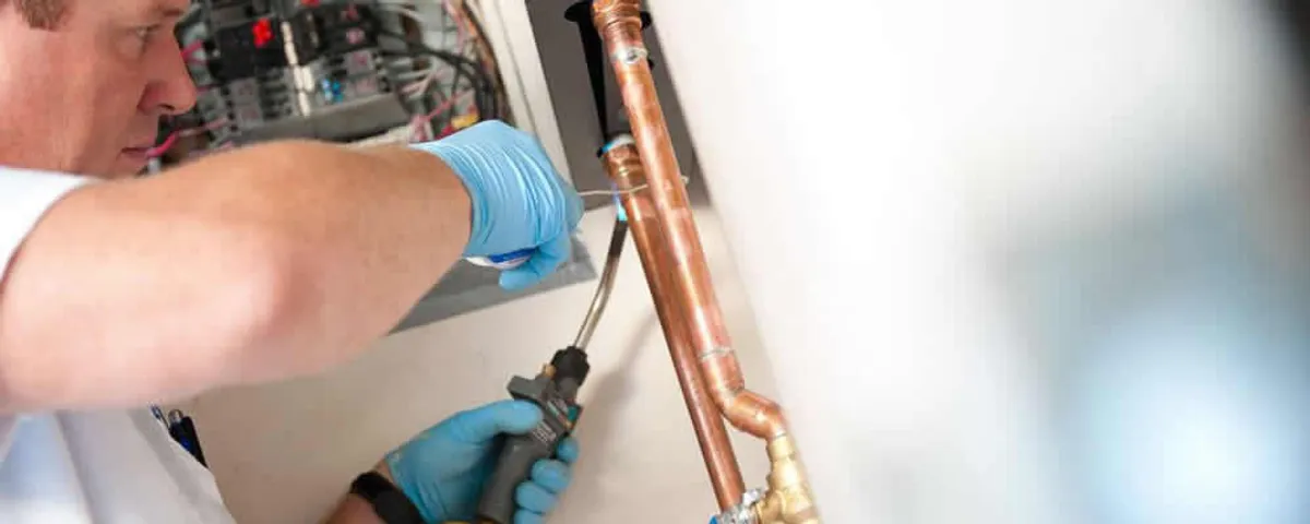 Water heater repair technician testing copper pipe connections and controls in Pittsburgh, PA